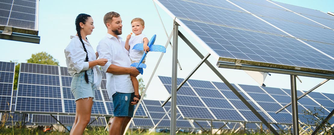 Familia Joven con un bebe paseando entre paneles solares en un campo de endesa